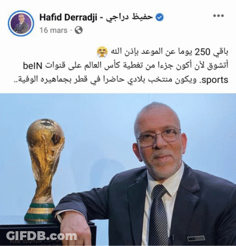 A Man In A Suit And Tie Is Standing Next To A Trophy That Says Fifa World Cup GIF