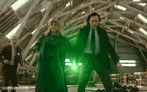 A Man In A Suit And Tie Is Standing Next To A Woman And A Man In A Suit GIF