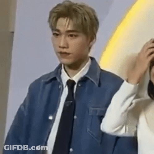 A Man In A Suit And Tie Is Standing Next To A Woman . GIF