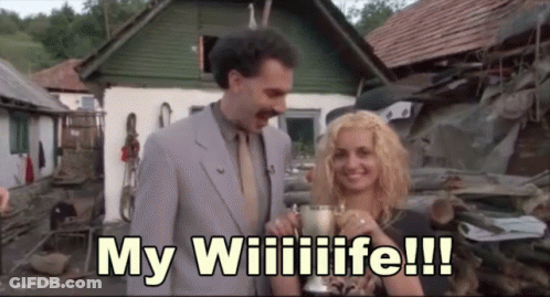 A Man In A Suit And Tie Is Standing Next To A Woman Holding A Trophy And Says My Wiilife !!! GIF
