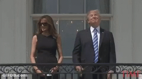 A Man In A Suit And Tie Is Standing Next To A Woman In A Black Dress . GIF