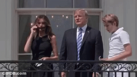 A Man In A Suit And Tie Is Standing Next To A Woman In A Black Dress And A Boy . GIF