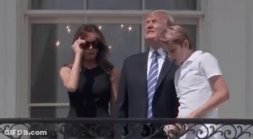 A Man In A Suit And Tie Is Standing Next To A Woman In A Black Dress And A Man In A White Shirt . GIF