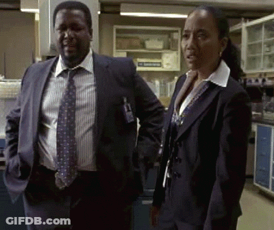 A Man In A Suit And Tie Is Standing Next To A Woman In A Suit GIF