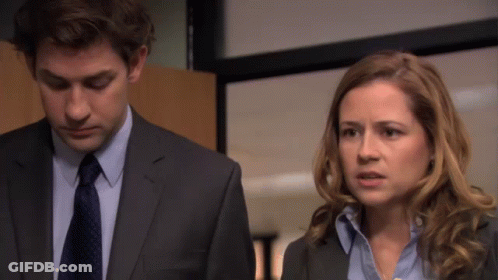 A Man In A Suit And Tie Is Standing Next To A Woman GIF