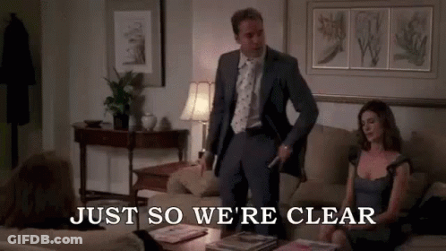 A Man In A Suit And Tie Is Standing Next To A Woman On A Couch In A Living Room . GIF