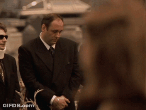A Man In A Suit And Tie Is Standing Next To A Woman GIF