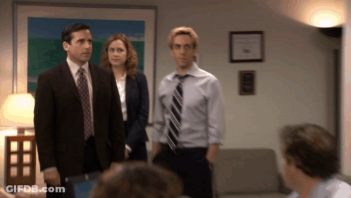 A Man In A Suit And Tie Is Standing Next To A Woman GIF