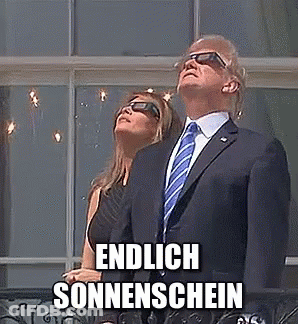 A Man In A Suit And Tie Is Standing Next To A Woman Wearing Sunglasses And Looking Up At The Sun . GIF