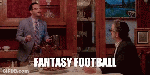 A Man In A Suit And Tie Is Standing Next To Another Man At A Table And Says Fantasy Football . GIF