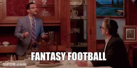 A Man In A Suit And Tie Is Standing Next To Another Man At A Table And Says Fantasy Football GIF