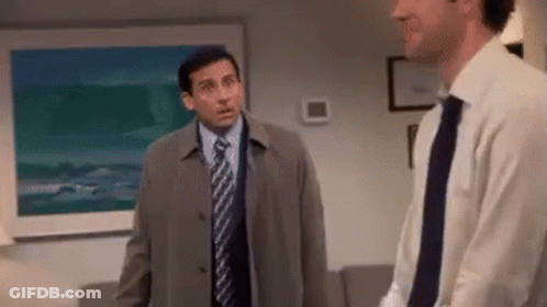 A Man In A Suit And Tie Is Standing Next To Another Man In A Living Room . GIF