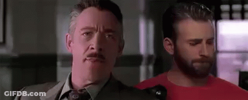 A Man In A Suit And Tie Is Standing Next To Another Man In A Red Shirt In A Room . GIF