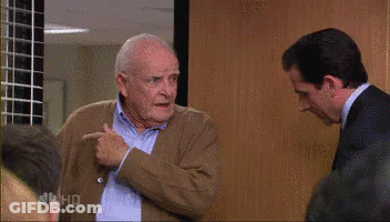 A Man In A Suit And Tie Is Standing Next To Another Man In A Sweater . GIF