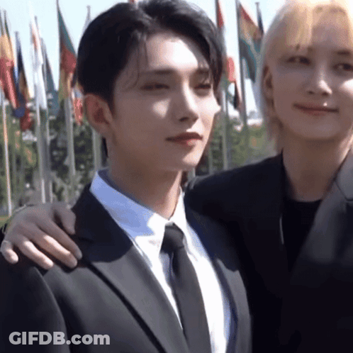 A Man In A Suit And Tie Is Standing Next To Another Man GIF