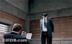 A Man In A Suit And Tie Is Standing Next To Another Man . GIF