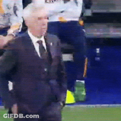A Man In A Suit And Tie Is Standing On A Field GIF