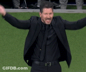 A Man In A Suit And Tie Is Standing On A Field With His Arms Outstretched . GIF