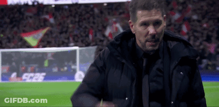 A Man In A Suit And Tie Is Standing On A Soccer Field With A Crowd In The Background . GIF