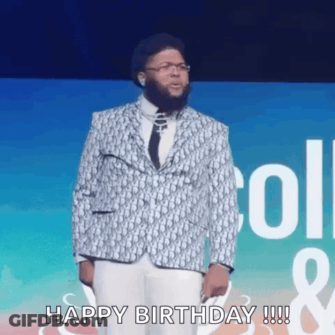 A Man In A Suit And Tie Is Standing On A Stage And Says `` Happy Birthday '' . GIF
