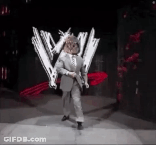 A Man In A Suit And Tie Is Standing On A Stage Holding Two Guns . GIF