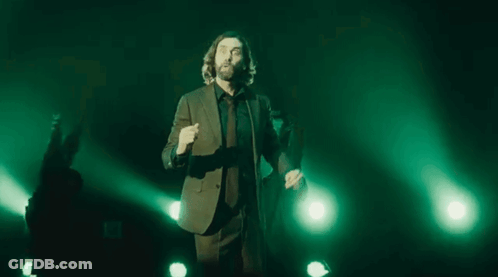 Man In Suit And Tie With Outstretched Arms On Stage GIF