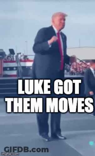 A Man In A Suit And Tie Is Standing On A Stage With The Caption Luke Got Them Moves GIF