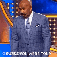 A Man In A Suit And Tie Is Standing On A Stage With The Words `` Guess You Were Told '' . GIF