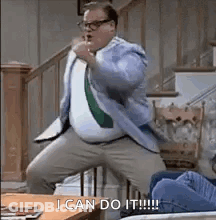 A Man In A Suit And Tie Is Standing On A Staircase . GIF
