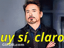 A Man In A Suit And Tie Is Standing With His Arms Crossed In Front Of A Sign That Says Uy Si Claro . GIF