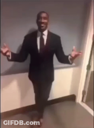 A Man In A Suit And Tie Is Standing With His Arms Outstretched . GIF