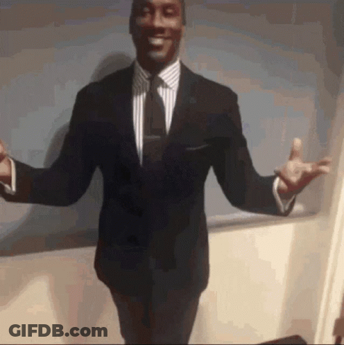 A Man In A Suit And Tie Is Standing With His Arms Outstretched And Smiling GIF