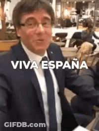 A Man In A Suit And Tie Is Taking A Selfie With The Words Viva Espana On The Bottom . GIF