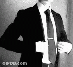 A Man In A Suit And Tie Is Taking Off His Jacket . GIF