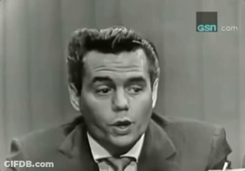 A Man In A Suit And Tie Is Talking In Front Of A Sign That Says Gsn.com GIF
