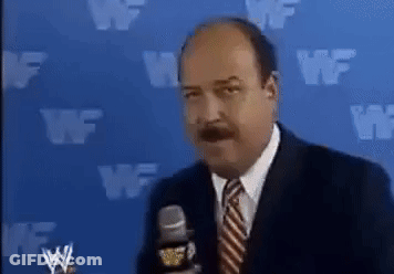A Man In A Suit And Tie Is Talking Into A Microphone In Front Of A Blue Wall With Wf Written On It . GIF