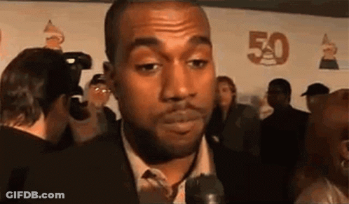 A Man In A Suit And Tie Is Talking Into A Microphone While Standing In Front Of A Crowd . GIF