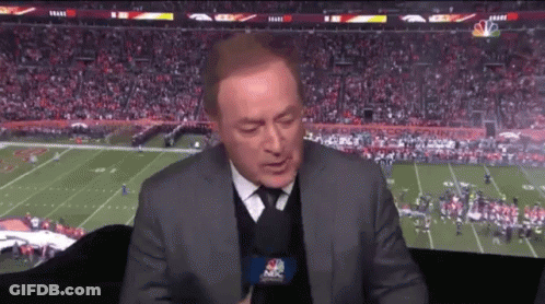 A Man In A Suit And Tie Is Talking Into A Microphone While Watching A Football Game On Nbc GIF