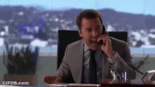 A Man In A Suit And Tie Is Talking On A Cell Phone . GIF