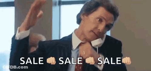 A Man In A Suit And Tie Is Talking On A Cell Phone While Making A Fist Gesture . GIF