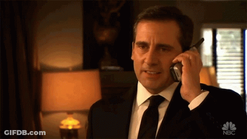 A Man In A Suit And Tie Is Talking On A Cell Phone With The Nbc Logo Visible GIF