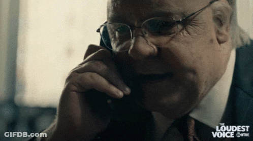 A Man In A Suit And Tie Is Talking On A Phone With The Words " The Loudest Voice " Behind Him GIF