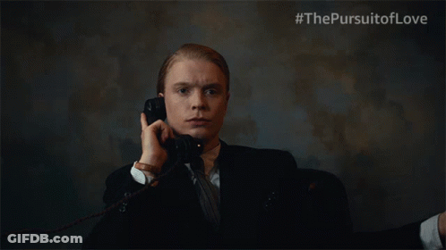 A Man In A Suit And Tie Is Talking On A Phone With #Thepursuitoflove Written On The Bottom Right GIF