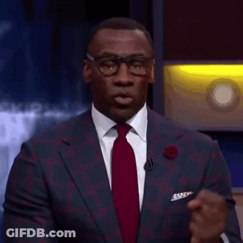 A Man In A Suit And Tie Is Talking On A Stage GIF