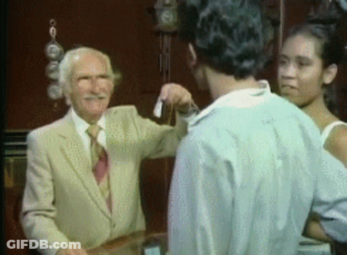 A Man In A Suit And Tie Is Talking To A Man And A Woman . GIF