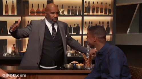 A Man In A Suit And Tie Is Talking To A Man In A Blue Shirt GIF