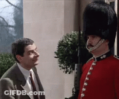 A Man In A Suit And Tie Is Talking To A Man In A Red Uniform With A Hat On . GIF