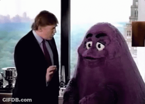 A Man In A Suit And Tie Is Talking To A Purple Monster In Front Of A Window . GIF