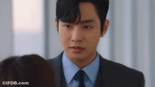 A Man In A Suit And Tie Is Talking To A Woman . GIF