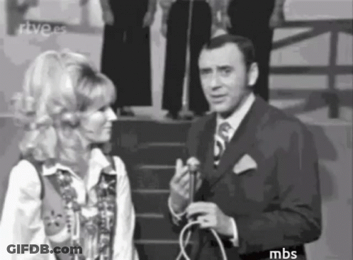 A Man In A Suit And Tie Is Talking To A Woman In A Black And White Photo . GIF